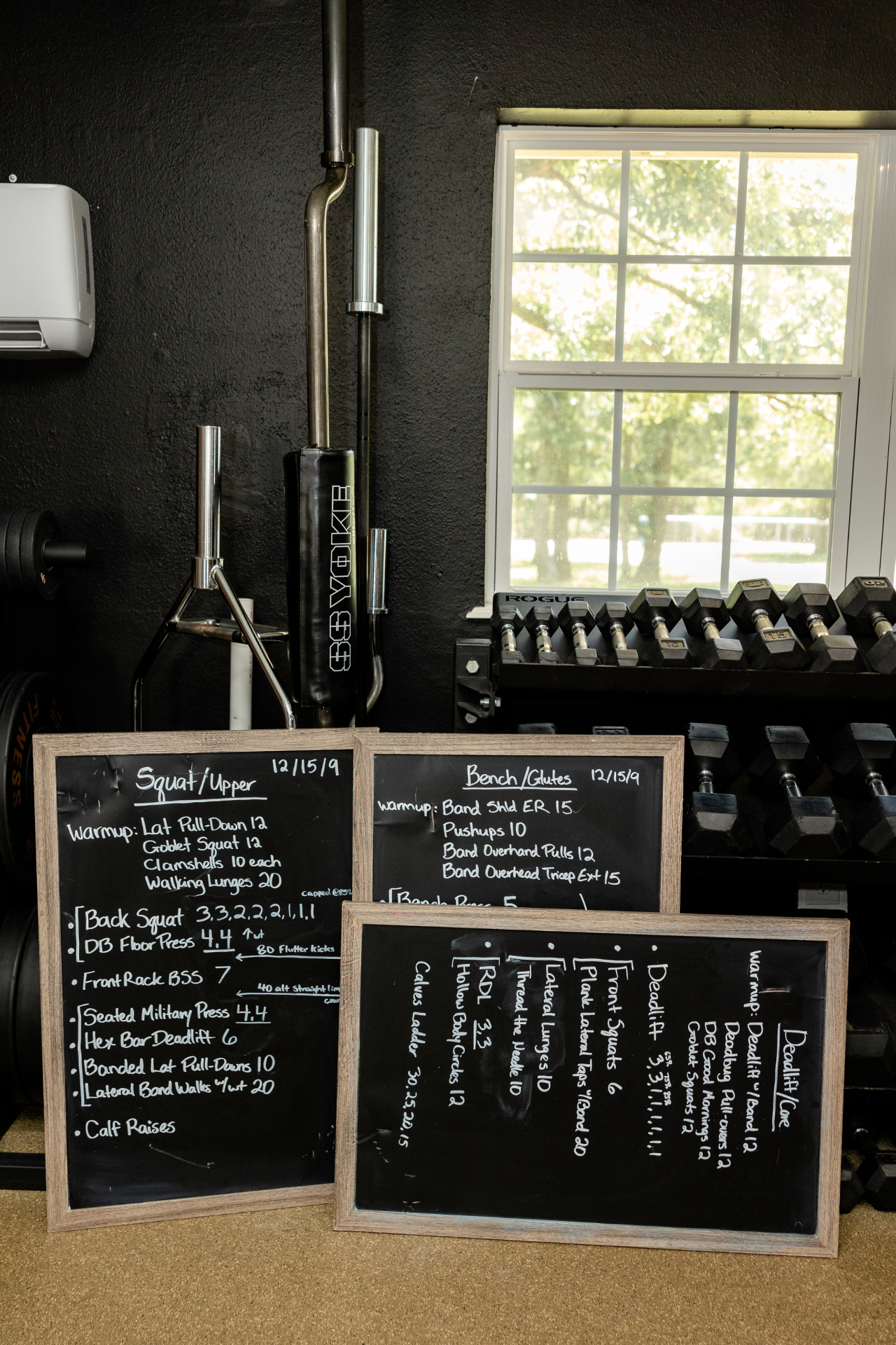 Whiteboards in the studio detailing the squat, bench, and deadlift training days